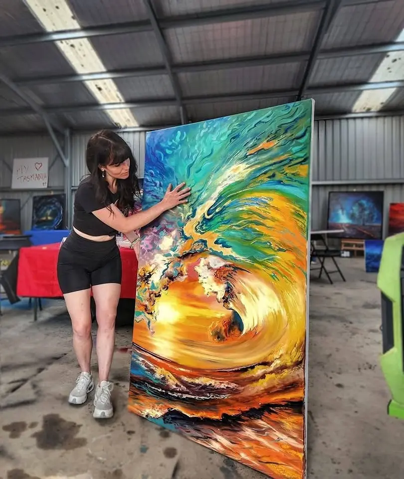 Artist touching large vibrant abstract painting in studio