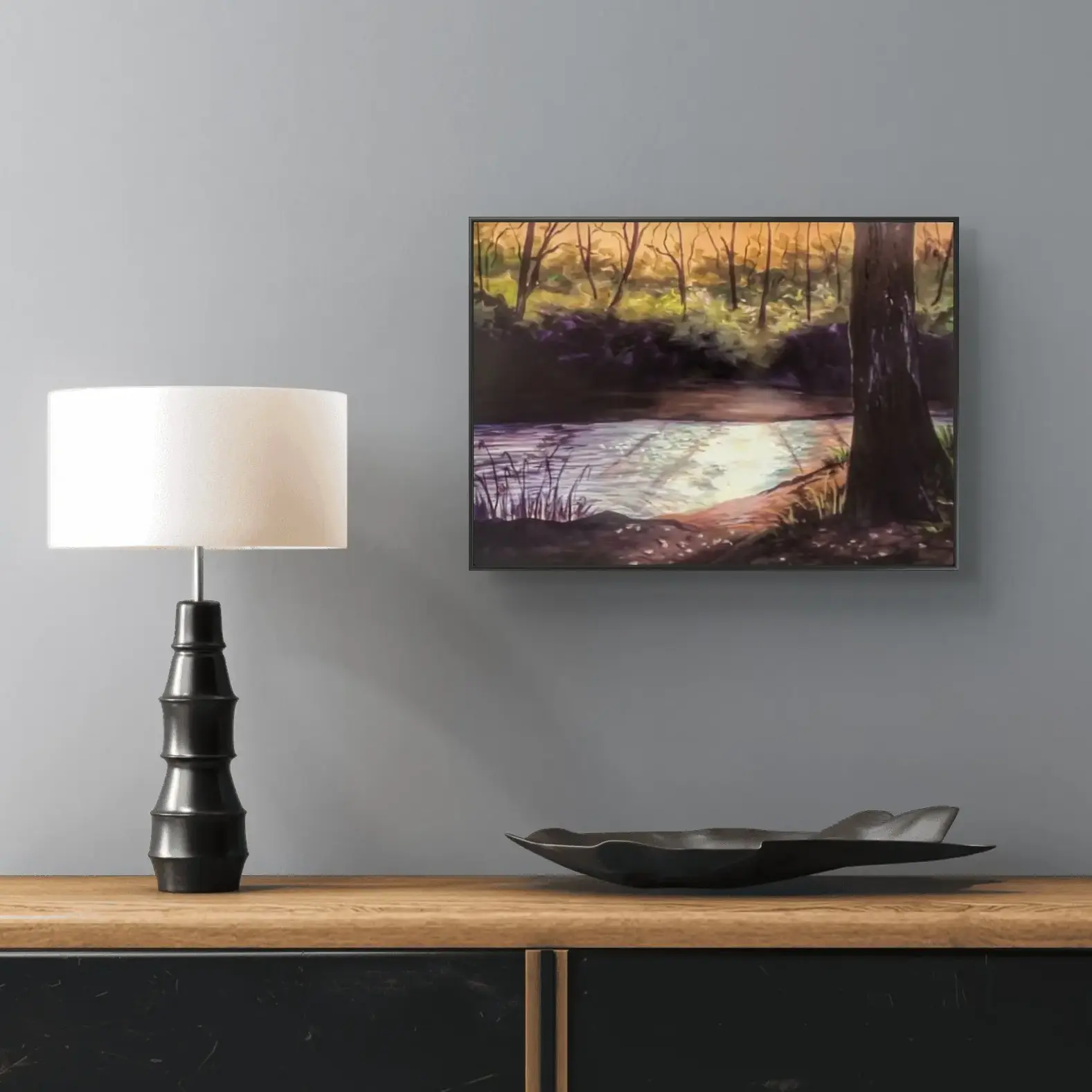 Framed forest river painting above wooden sideboard