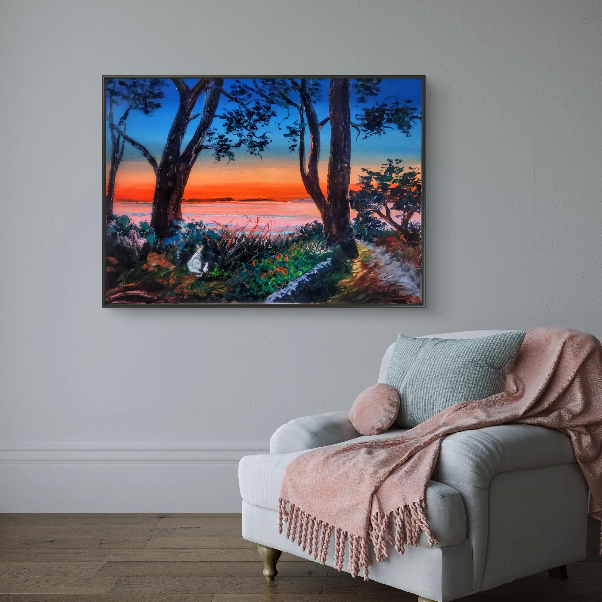 Framed coastal sunset painting above armchair