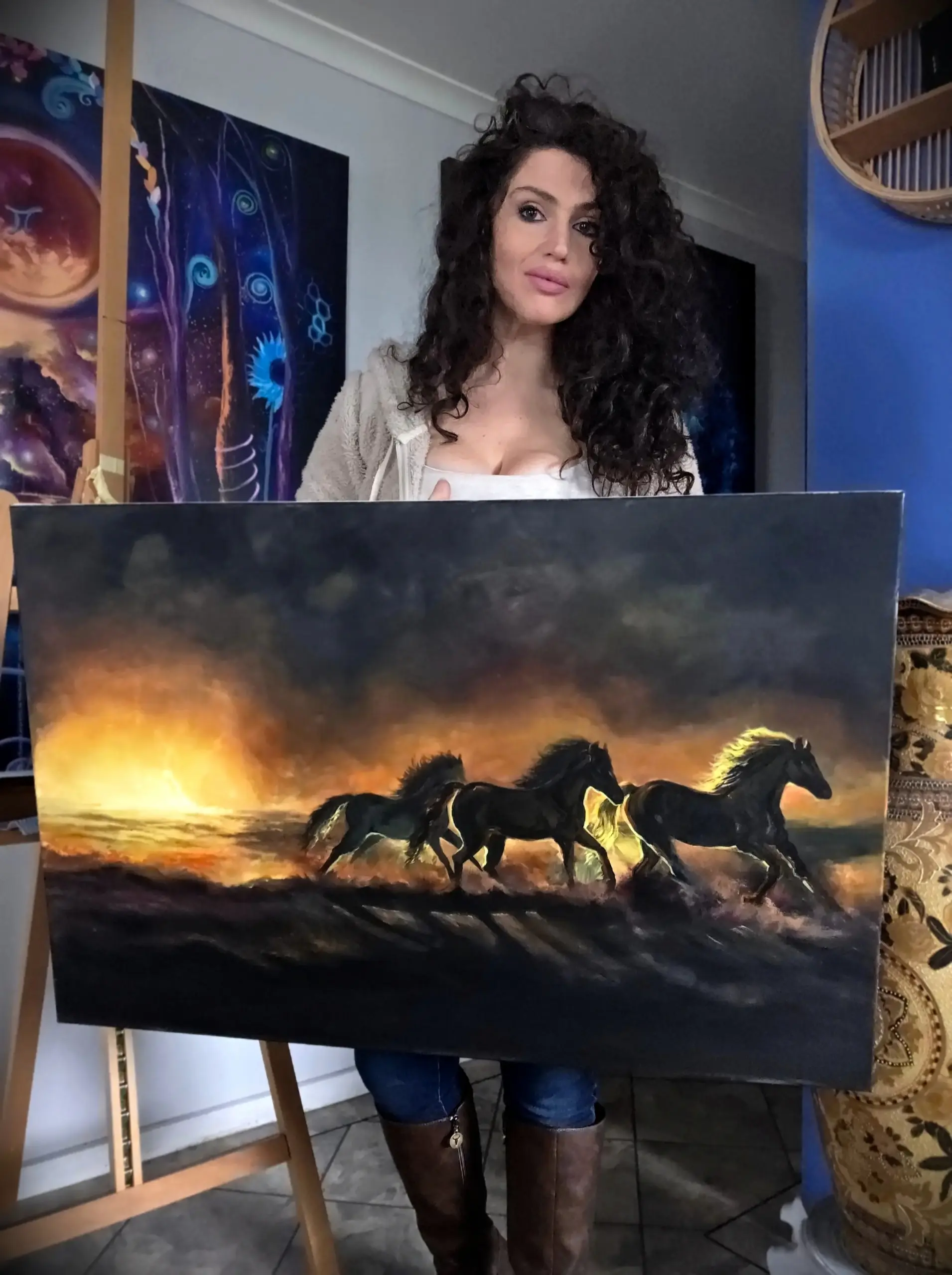 1000155260 Artist holding painting of running horses at sunset